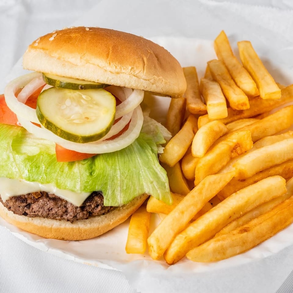Cheeseburger with lettuce, tomato, onion, and pickles, served with a side of golden french fries.