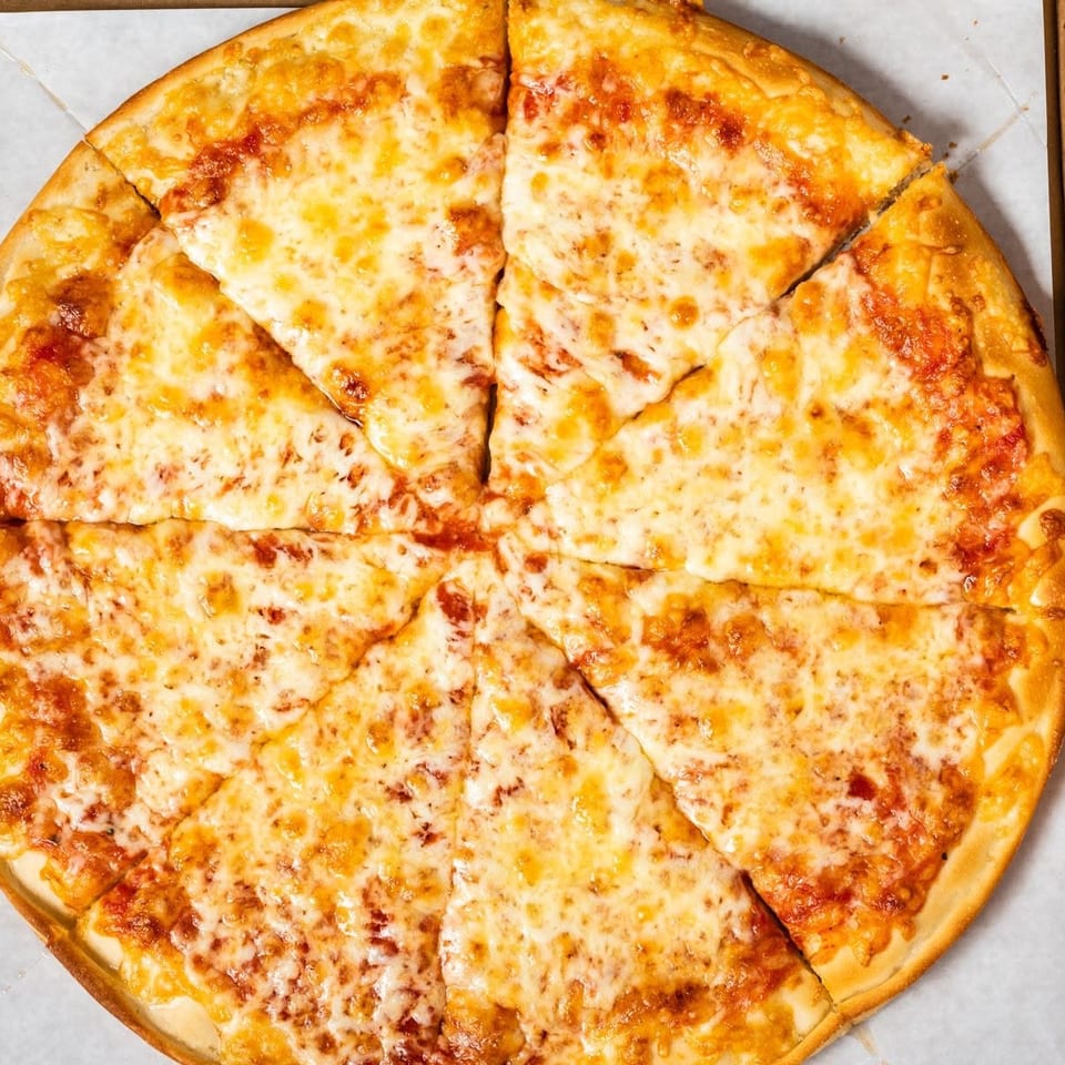A freshly baked cheese pizza, sliced into eight pieces, rests inside a cardboard delivery box.